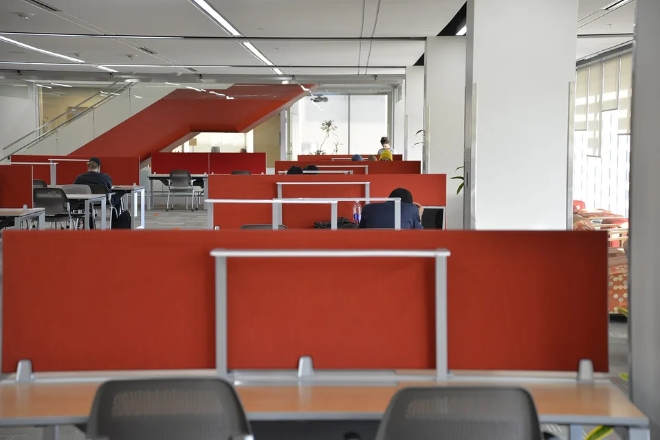 Estudantes trabalham em computadores portáteis numa biblioteca universitária.